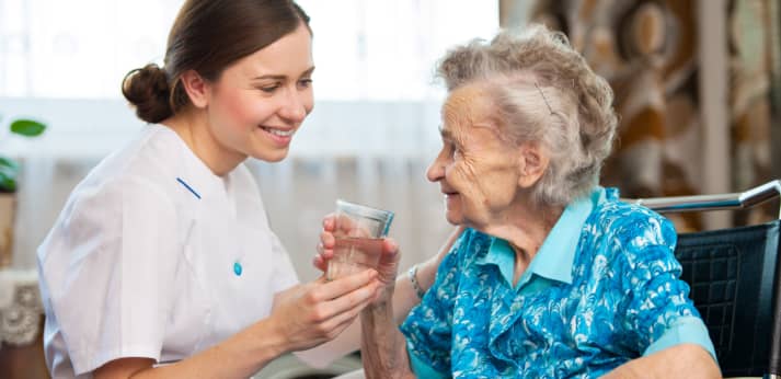 caregiver giving a glass of water to the senior woman